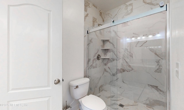 bathroom featuring a marble finish shower and toilet