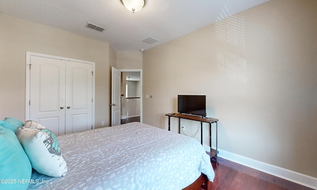 bedroom with visible vents, dark wood finished floors, baseboards, and a closet