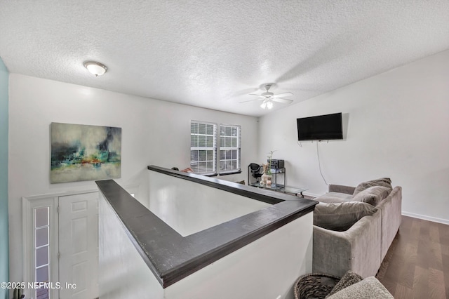 living room featuring a textured ceiling, ceiling fan, dark wood-style floors, and baseboards