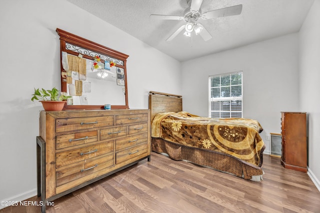 bedroom with baseboards, a textured ceiling, ceiling fan, and wood finished floors