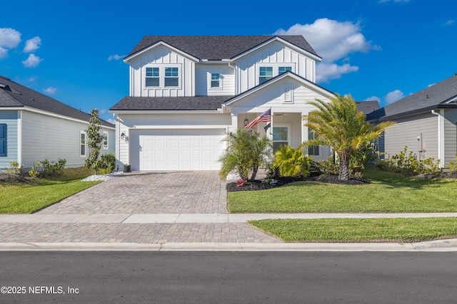view of front of property with an attached garage, decorative driveway, board and batten siding, and a front yard