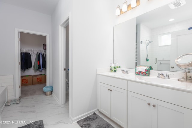 full bath featuring double vanity, a walk in closet, a stall shower, a sink, and marble finish floor