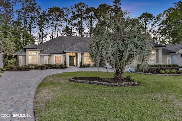 view of front of property featuring curved driveway, stucco siding, and a front lawn
