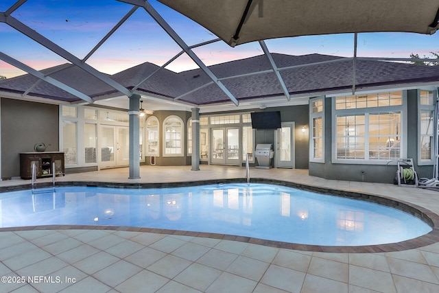 outdoor pool with french doors, glass enclosure, a grill, and a patio area