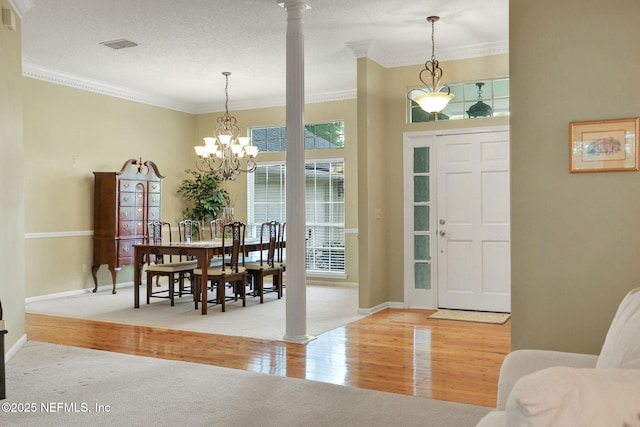 entrance foyer featuring decorative columns, crown molding, wood finished floors, baseboards, and a notable chandelier