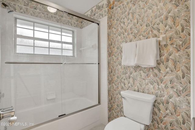 bathroom featuring bath / shower combo with glass door, wallpapered walls, and toilet