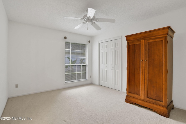 unfurnished bedroom featuring a closet, a ceiling fan, a textured ceiling, and light colored carpet