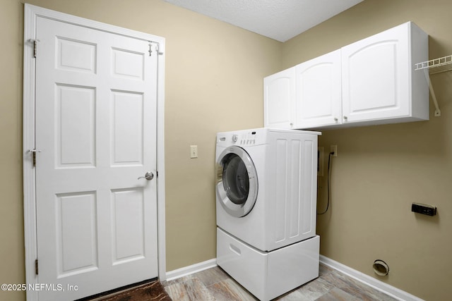 laundry room with baseboards, cabinet space, and washer / clothes dryer