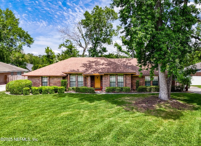 ranch-style house featuring a front lawn, roof with shingles, fence, and brick siding