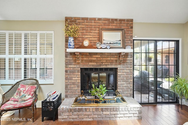 living room with hardwood / wood-style flooring and a brick fireplace