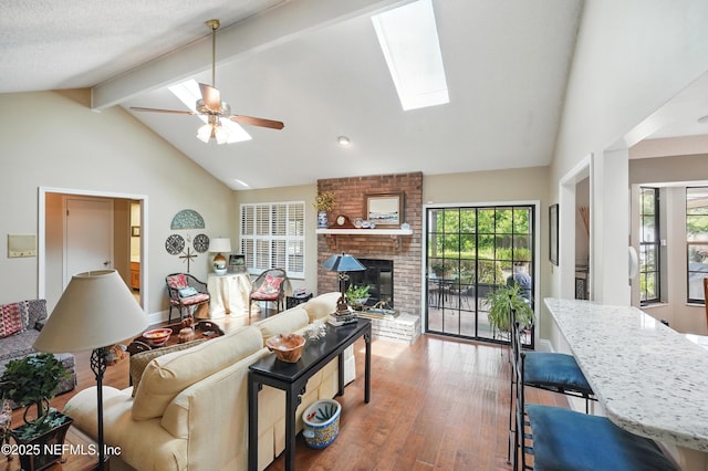 living room with a brick fireplace, a skylight, wood finished floors, and a healthy amount of sunlight