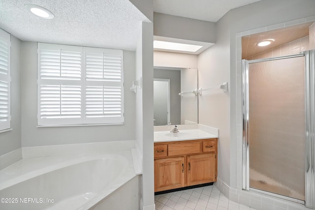 bathroom featuring a skylight, vanity, a bath, a stall shower, and tile patterned flooring