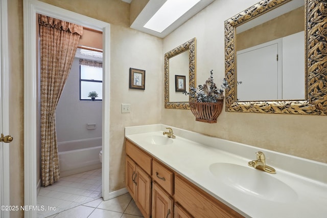 bathroom featuring toilet, double vanity, a sink, and tile patterned floors