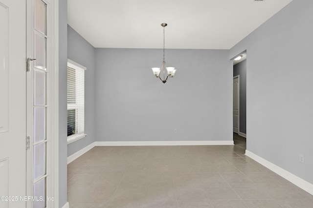 tiled empty room featuring baseboards and a chandelier