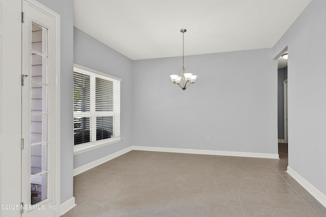 empty room featuring baseboards, a notable chandelier, and tile patterned floors