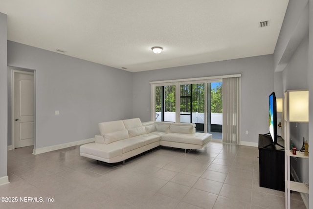 living room featuring baseboards, light tile patterned flooring, and visible vents