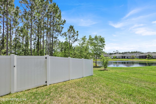view of yard with fence, a water view, and a residential view
