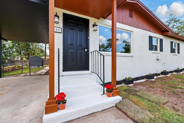 doorway to property with brick siding and fence