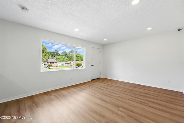 unfurnished room with recessed lighting, a textured ceiling, baseboards, and wood finished floors