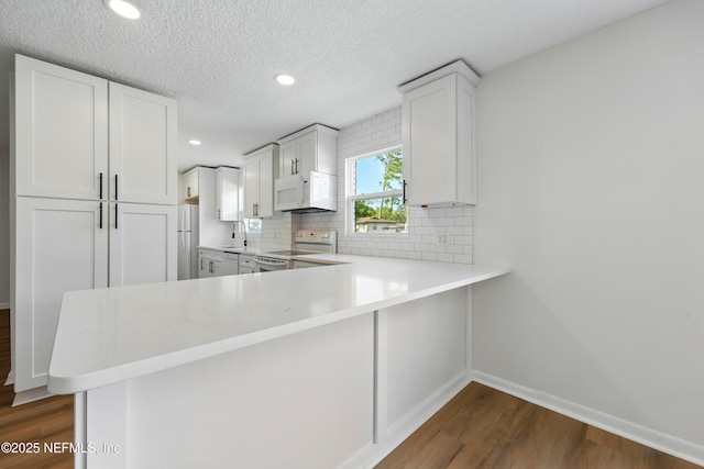 kitchen featuring white appliances, light countertops, white cabinetry, decorative backsplash, and dark wood-style floors