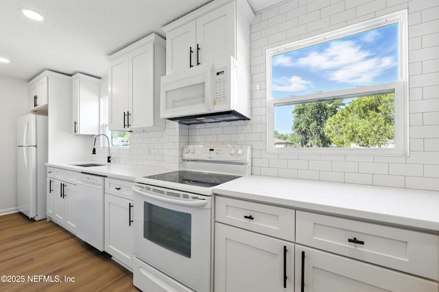 kitchen featuring a sink, recessed lighting, decorative backsplash, and white appliances