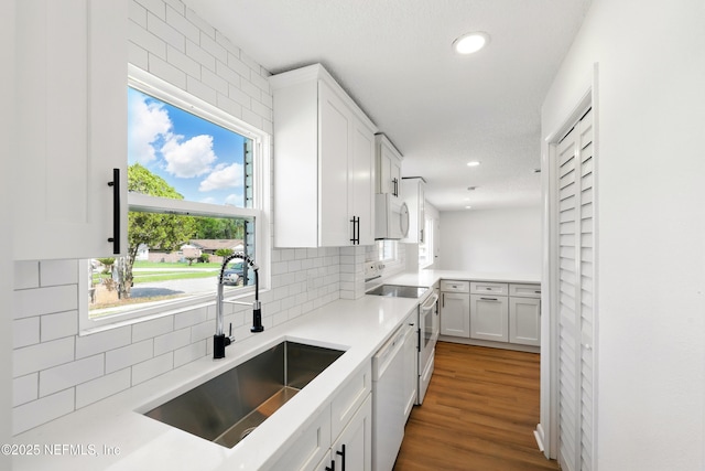 kitchen featuring decorative backsplash, a sink, white cabinets, recessed lighting, and white appliances