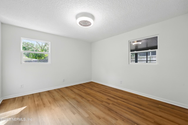 empty room featuring baseboards, a textured ceiling, and wood finished floors