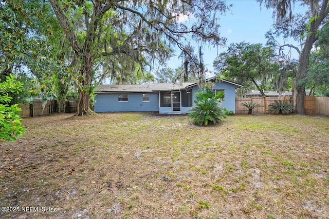 back of house with a lawn, a sunroom, and a fenced backyard