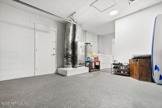 below grade area featuring concrete block wall, separate washer and dryer, water heater, and a textured ceiling