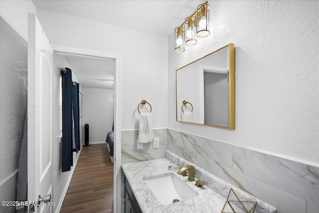 bathroom with wood finished floors, a textured wall, and vanity