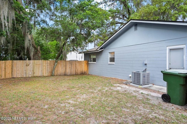 view of side of property with fence, cooling unit, and a yard