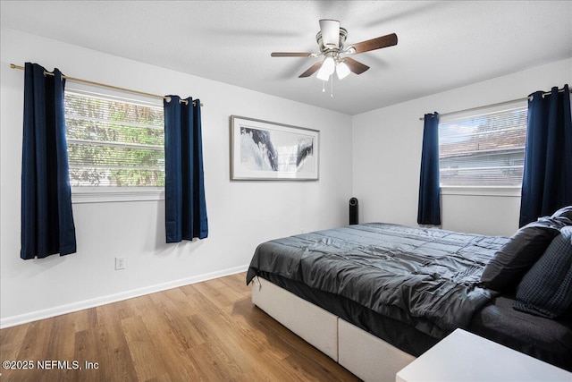 bedroom featuring wood finished floors, a ceiling fan, and baseboards