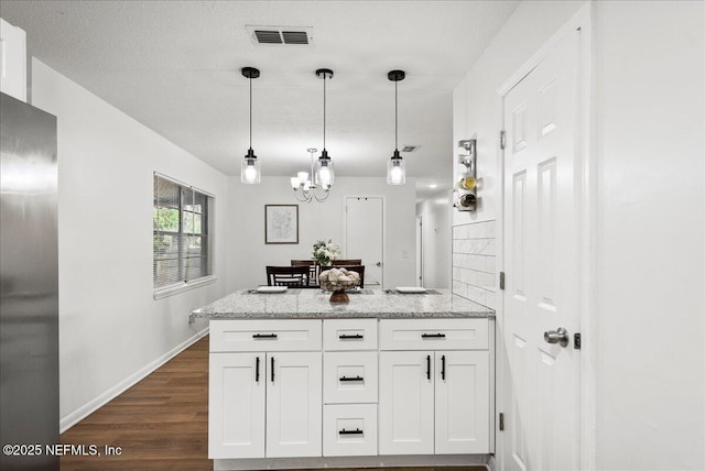 kitchen with light stone countertops, a notable chandelier, white cabinetry, and dark wood-type flooring