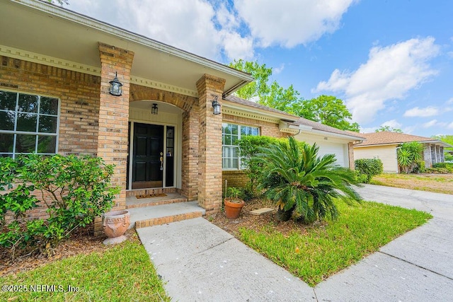 1218 Shallowford Dr E, Jacksonville, FL 32225 - view of exterior entry featuring brick siding, a garage, and driveway