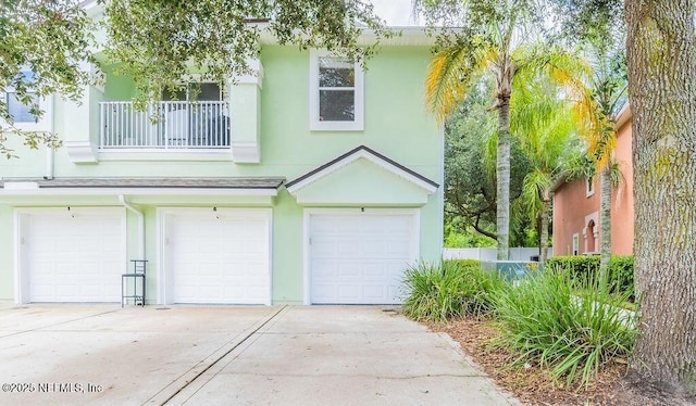 townhome / multi-family property featuring an attached garage, driveway, stucco siding, and a balcony