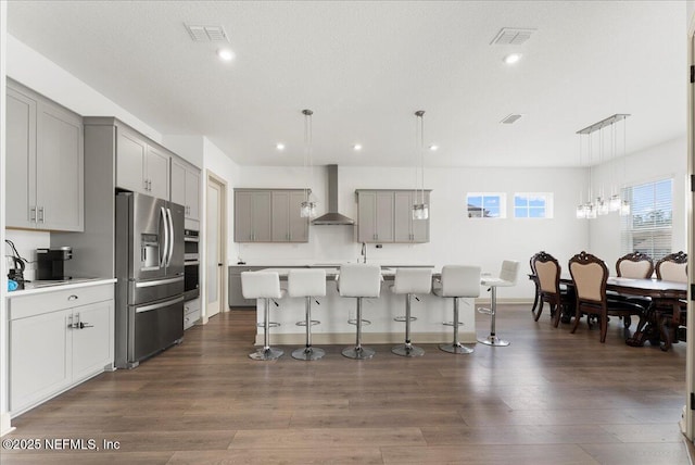 982 Oakland Hills Ave, Middleburg, FL 32068 - kitchen featuring appliances with stainless steel finishes, gray cabinetry, a breakfast bar, wall chimney exhaust hood, and dark wood-type flooring