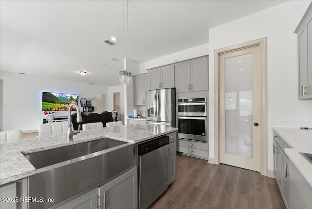 982 Oakland Hills Ave, Middleburg, FL 32068 - kitchen with visible vents, light stone counters, a sink, gray cabinetry, and stainless steel appliances