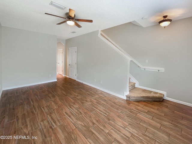 unfurnished living room with wood finished floors, visible vents, ceiling fan, and arched walkways