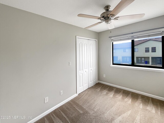 unfurnished bedroom featuring a closet, carpet flooring, a ceiling fan, and baseboards