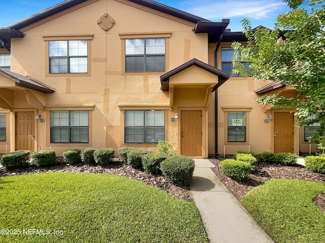 view of front of house featuring stucco siding and a front yard