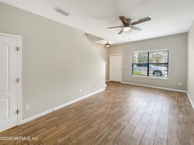 unfurnished room featuring baseboards, visible vents, wood finished floors, and a ceiling fan