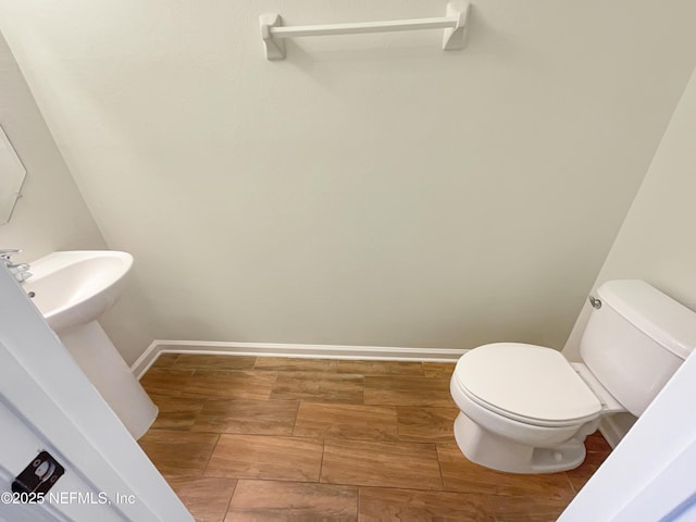 half bathroom featuring toilet, a sink, and wood finished floors