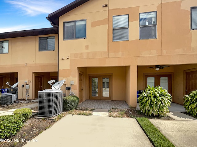 view of front of property with french doors, stucco siding, and central AC unit