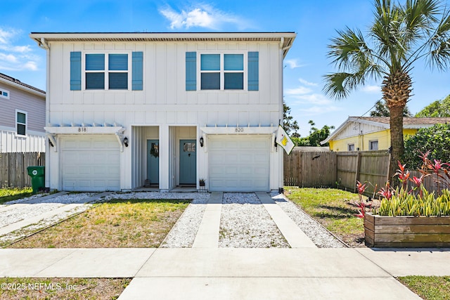 traditional-style house with fence, board and batten siding, an attached garage, and driveway