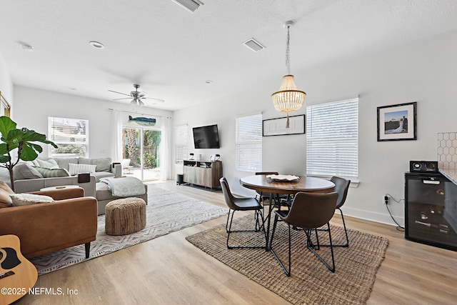 dining room with baseboards, visible vents, ceiling fan with notable chandelier, and light wood-type flooring