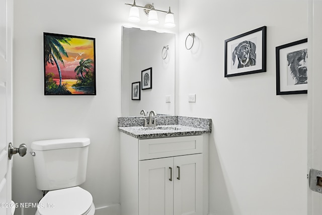 half bathroom featuring toilet, baseboards, and vanity