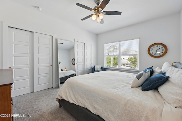 bedroom featuring carpet floors, ceiling fan, and two closets