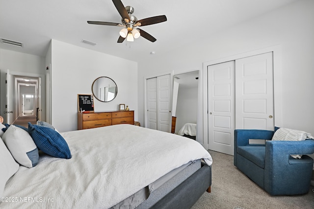 bedroom with a ceiling fan, multiple closets, visible vents, and carpet