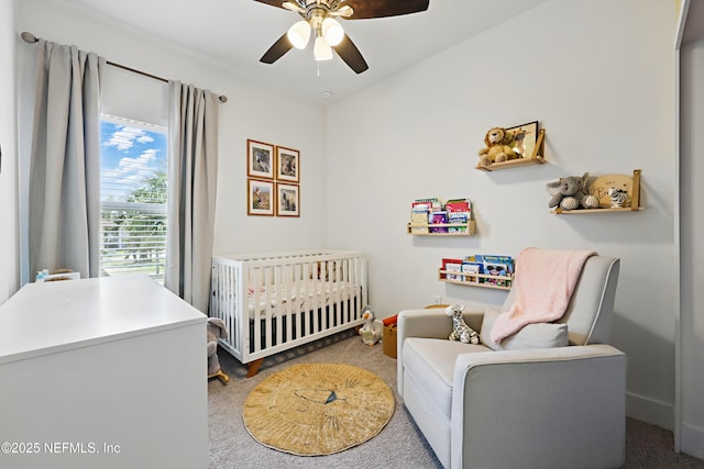 bedroom with carpet floors, ceiling fan, a crib, and baseboards