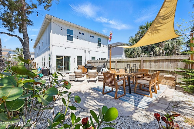 rear view of property featuring fence, board and batten siding, and a patio area